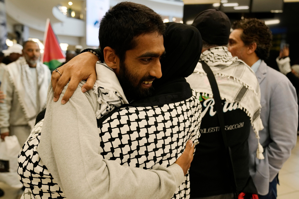 Yusuf Rahman, an activist embraces his family member after returning home at OR Tambo International Airport, in Johannesburg, South Africa, Saturday, May 23, 2026. (AP Photo/Themba Hadebe)