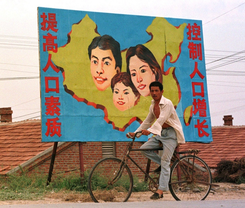 FILE - A farmer rides past a billboard which promotes China's one-child policy, on the outskirts of a village near Dongying, in Shandong province, Aug. 18, 1997. (AP Photo/Greg Baker, File)