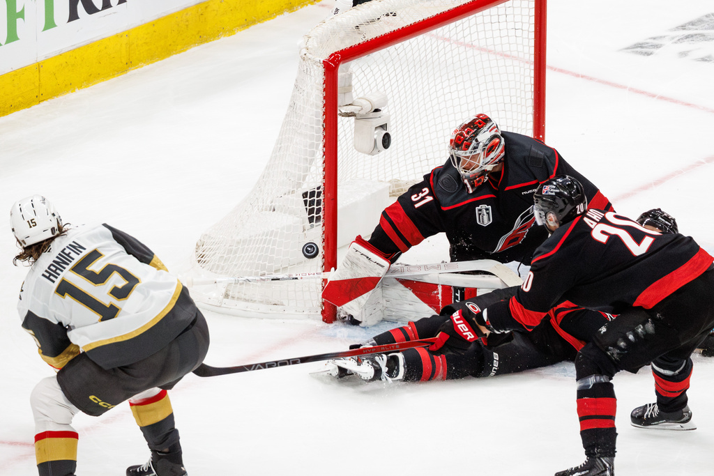 Carolina Hurricanes' goaltender Frederik Andersen (31) reaches for a puck as Vegas Golden Knights' Noah Hanifin (15) skates past during the first period of Game 1 of the NHL hockey Stanley Cup Final series in Raleigh, N.C., Tuesday, June 2, 2026. (AP Photo/Ben McKeown)