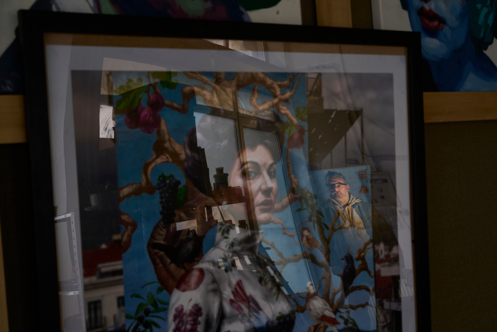 Artist Kleomenis Kostopoulos is reflected on poster with the mural he created depicting opera legend Maria Callas inside his workshop in Patras city about 215 kilometres (134 miles) west of Athens, Tuesday, Feb. 10, 2026. (AP Photo/Petros Giannakouris)