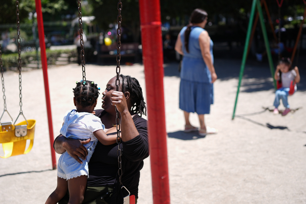 Vivianne Petit Frere holds her granddaughter Alexca as she swings with her at a playground, June 22, 2026, in Tijuana, Mexico. (AP Photo/Gregory Bull)