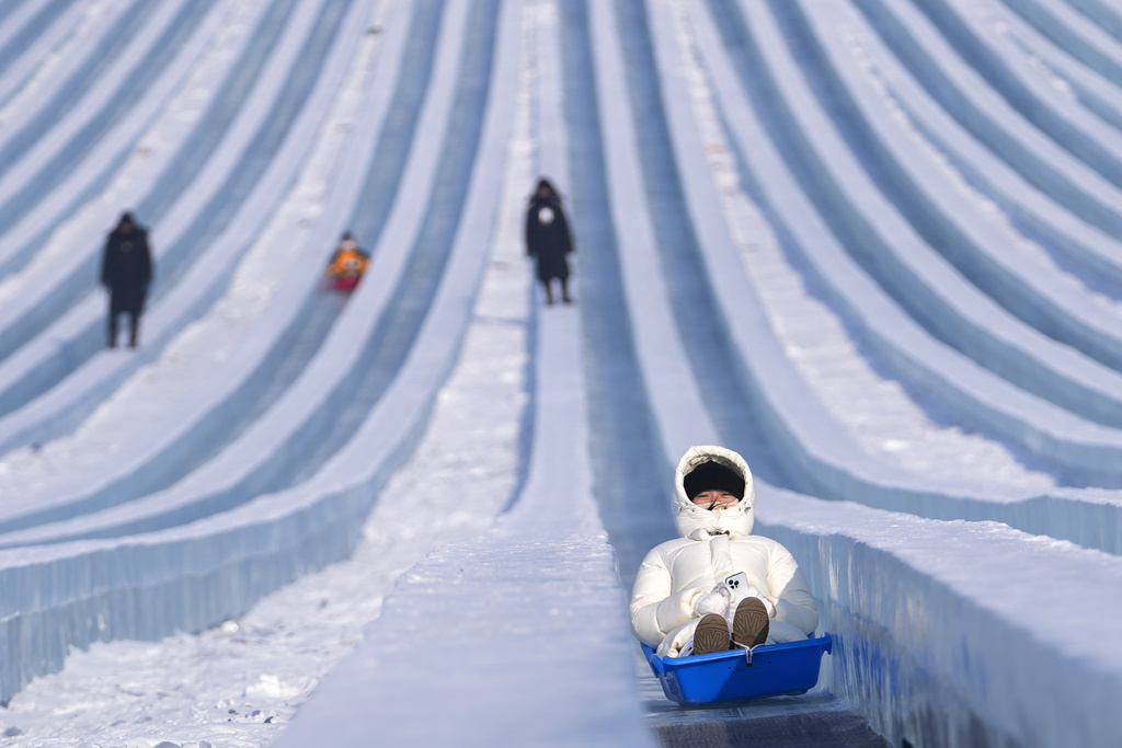 Visitors ride a giant ice block slides at the Harbin Ice and Snow World in Harbin, China's Heilongjiang province on Monday, Jan. 6, 2025. (AP Photo/Andy Wong)