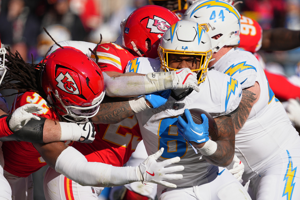 Los Angeles Chargers running back Omarion Hampton (8) is tackled by Kansas City Chiefs linebacker Nick Bolton (32) and linebacker Drue Tranquill during the first half of an NFL football game Sunday, Dec. 14, 2025, in Kansas City, Mo. (AP Photo/Ed Zurga)