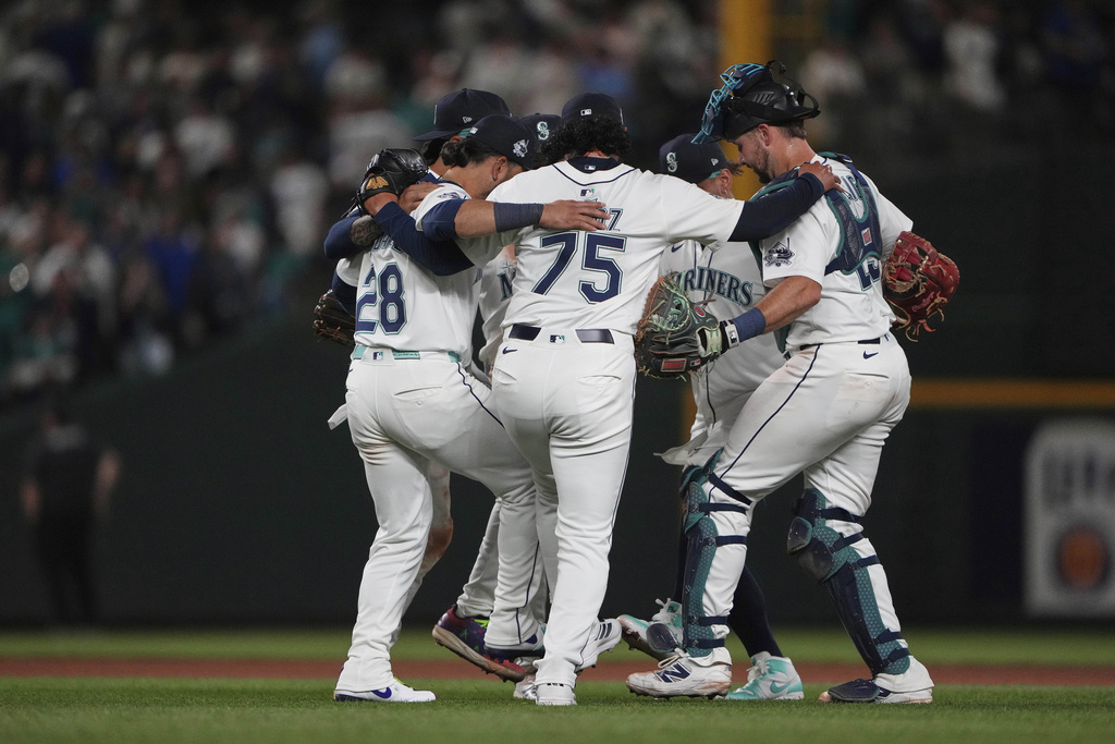 Seattle Mariners relief pitcher Andrés Muñoz (75) celebrates a win over the Tampa Bay Rays with the infield, including third baseman Eugenio Suarez (28) after a baseball game Saturday, Aug. 9, 2025, in Seattle. (AP Photo/Lindsey Wasson)