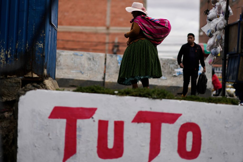 A woman walks past a mural promoting presidential candidate Jorge "Tuto" Quiroga ahead of the runoff election, in El Alto, Bolivia, Thursday, Oct. 16, 2025. (AP Photo/Natacha Pisarenko)
