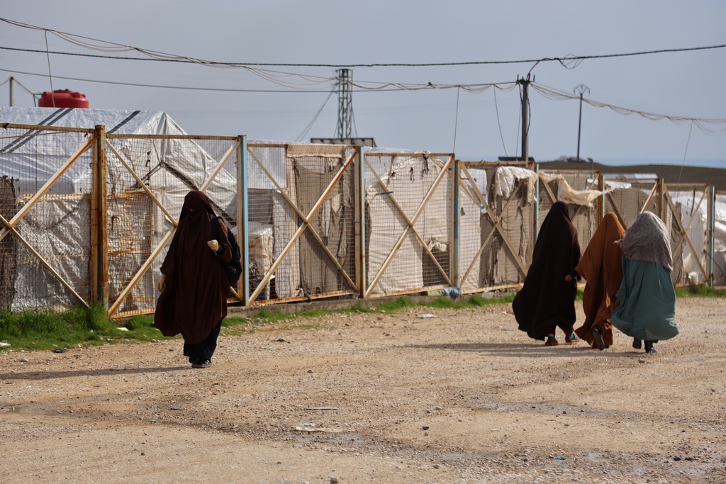 Unidentified women move through the camp holding family members of suspected Islamic State militants in the Roj Camp in eastern Syria, Wednesday, Feb. 18, 2026. (AP Photo/Baderkhan Ahmad)
