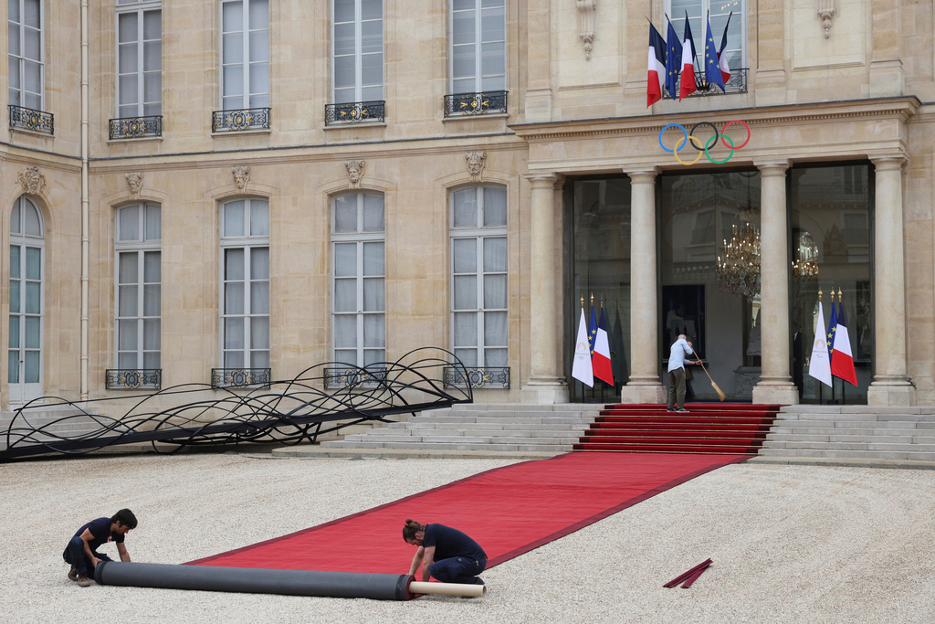 FILE - Workers prepare the red carpet before the heads of States' arrivals ahead of an opening ceremony in which thousands of Olympic athletes are due to sail down the Seine past iconic Parisian monuments, at the 2024 Summer Olympics, July 26, 2024, at the Elysee Palace in Paris. (AP Photo/Aurelien Morissard, File)