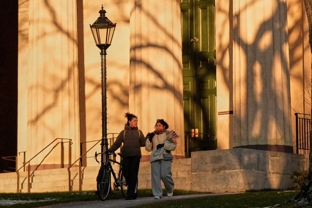 Brown University students Gloria Kuzmenko-Latimir, left, and Haleema Aslam walk by Manning Hall on their way to a makeshift memorial for the shooting victims, Tuesday, Dec. 16, 2025, in Providence, R.I. (AP Photo/Robert F. Bukaty)
