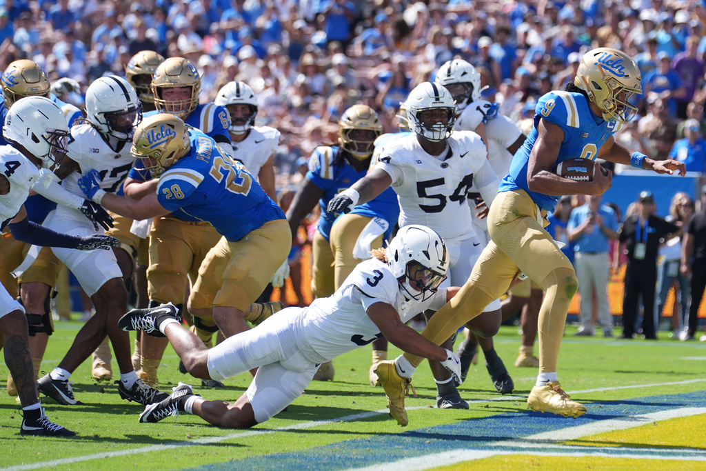 UCLA quarterback Nico Iamaleava (9) scores a rushing touchdown past Penn State cornerback Antoine Belgrave-Shorter (3) during the first half of an NCAA college football game Saturday, Oct. 4, 2025, in Pasadena, Calif. (AP Photo/Marcio Jose Sanchez)