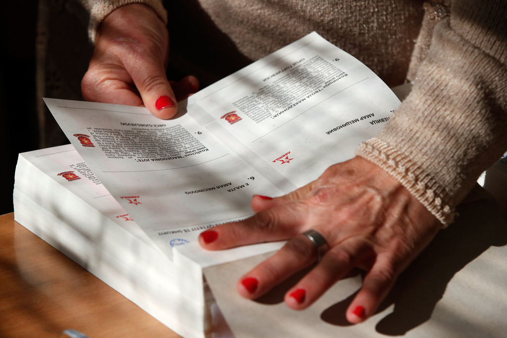 A member of the electoral commission prepares a ballot for voting in the runoff local elections, at a polling station in Skopje, North Macedonia, on Sunday, Nov. 2, 2025. (AP Photo/Boris Grdanoski)