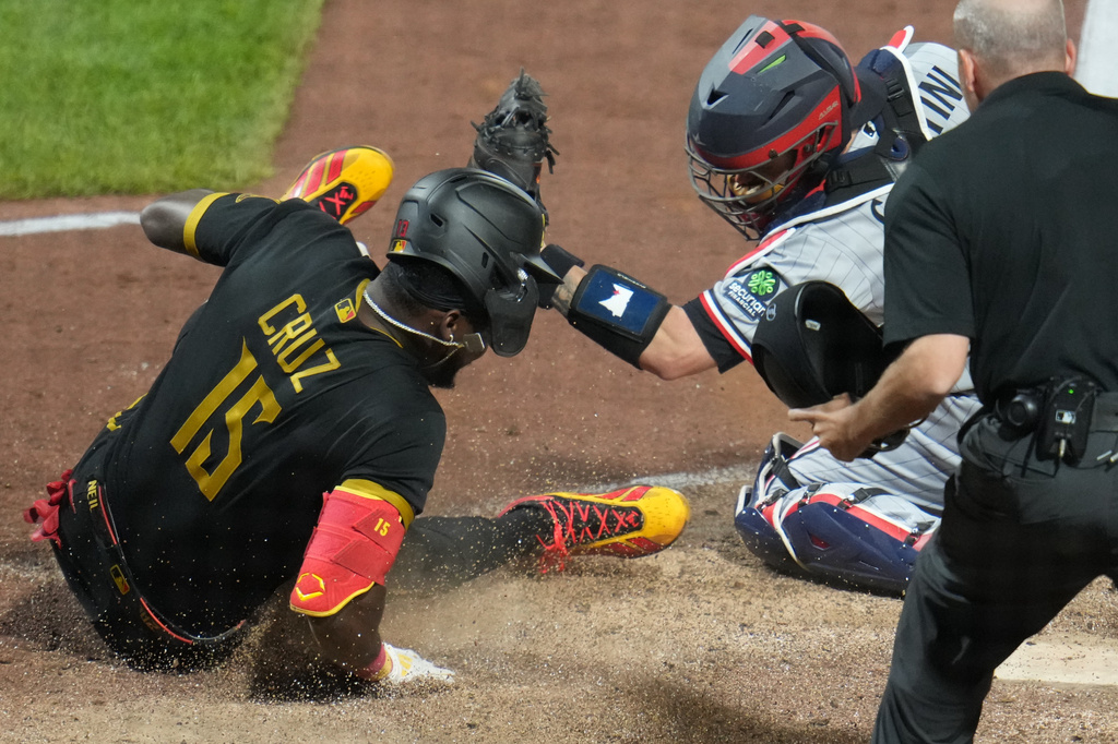 Pittsburgh Pirates' Oneil Cruz (15) is tagged out by Minnesota Twins catcher Victor Caratini, second from left, while attempting to score on a fielder's choice hit into by Jake Mangum during the eighth inning of a baseball game in Pittsburgh, Friday, May 29, 2026. (AP Photo/Gene J. Puskar)