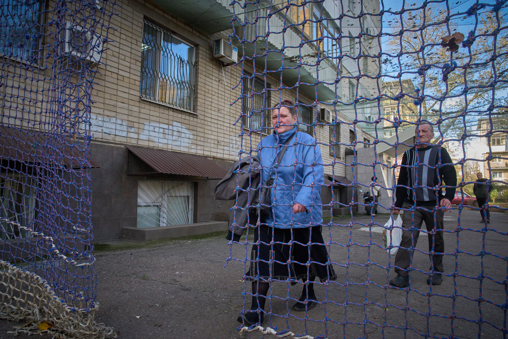 Local residents go along the street covered with an anti-FPV-drone net in the frontline city of Kherson, Southern Ukraine, Nov. 3, 2025. (AP Photo/Efrem Lukatsky)
