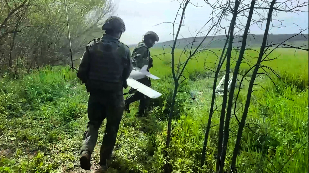 In this image made from video provided by Russian Defense Ministry Press Service on Wednesday, May 20, 2026, Russian servicemen carry an interceptor drone to launch for an action in an undisclosed location in Ukraine. (Russian Defense Ministry Press Service via AP)