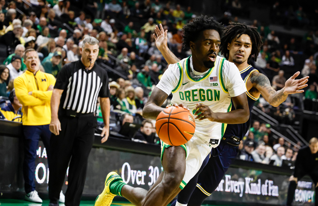 Oregon forward Dezdrick Lindsay (4) drives to the base against Michigan guard Elliot Cadeau (3) in the first half of an NCAA college basketball game in Eugene, Ore., Saturday, Jan. 17, 2026. (AP Photo/Thomas Boyd)