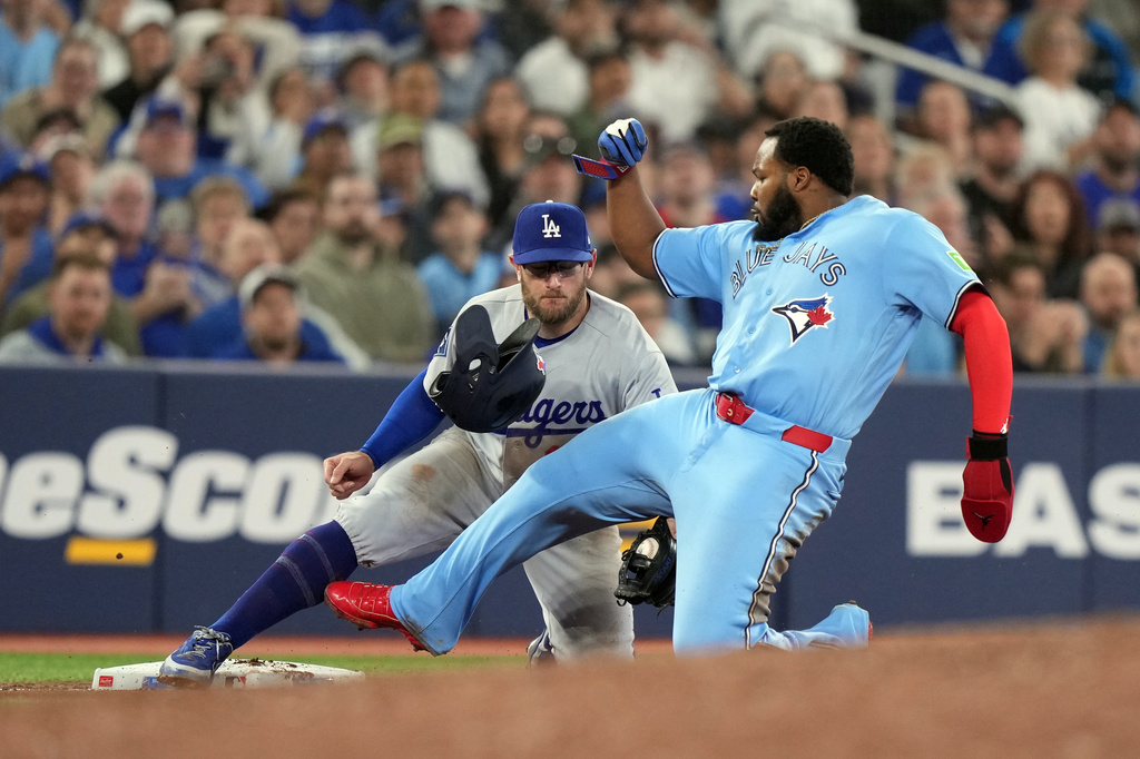 Los Angeles Dodgers third baseman Max Muncy (13) tags out Toronto Blue Jays Vladimir Guerrero Jr. (27) during the sixth inning of a baseball game in Toronto, Wednesday, April 8, 2026. (Nathan Denette/The Canadian Press via AP)