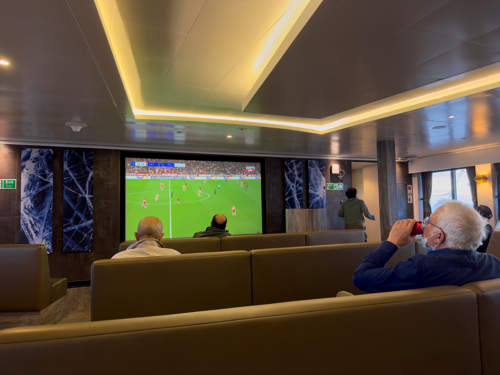 Passengers on the hantavirus-stricken cruise ship, MV Hondius, watch a football match on a television during their voyage to Spain's port of Tenerife, May 6, 2026. (AP Photo)