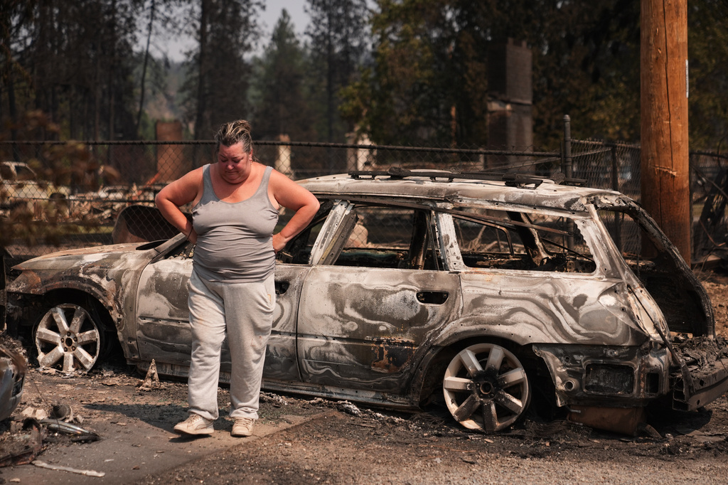 Michelle Angstrom reacts to her burned down home and property after a wildfire hit the northwest part of Spokane, Wash., Tuesday, Aug. 4, 2026. (AP Photo/Lindsey Wasson)