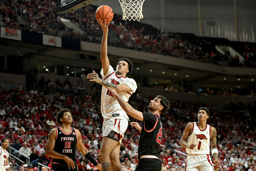 Arkansas forward Malique Ewin (12) drives past Fresno State guard Bastien Rieber (21) to score during the second half of an NCAA college basketball game Saturday, Dec. 6, 2025, in North Little Rock, Ark. (AP Photo/Michael Woods)