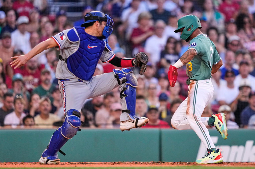 Boston Red Sox's Ceddanne Rafaela, right, beats a tag by Texas Rangers' Kyle Higashioka, left, to score on a sacrifice fly hit by Wilyer Abreu during the first inning of a baseball game, Friday, June 12, 2026, in Boston. (AP Photo/Charles Krupa)