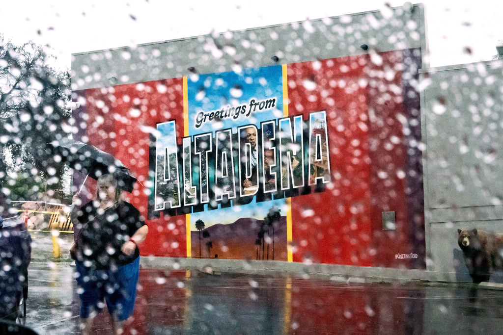 A woman walks past a mural in Altadena, Calif., as the region remains under flash flood warnings Saturday, Nov. 15, 2025. (AP Photo/Noah Berger)
