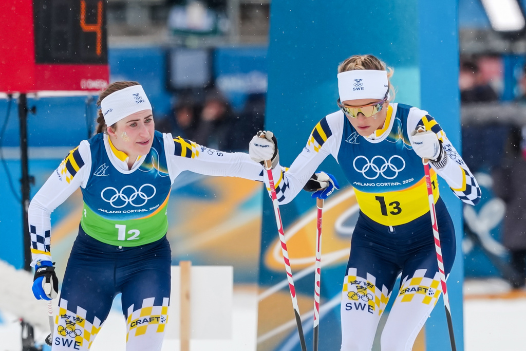 Ebba Andersson, of Sweden, tags teammate Frida Karlsson, right, during the cross country skiing women's 4 x 7.5km relay at the 2026 Winter Olympics, in Tesero, Italy, Saturday, Feb. 14, 2026. (AP Photo/Kirsty Wigglesworth)