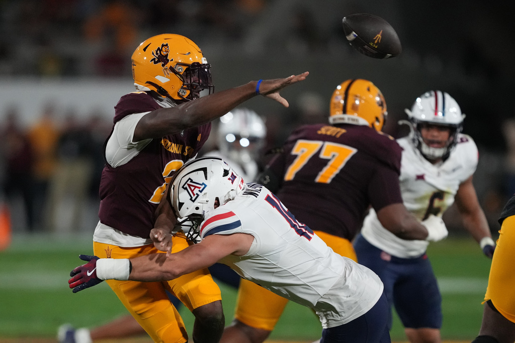 Arizona State quarterback Jeff Sims (2) throws the ball while getting pressured by Arizona linebacker Riley Wilson in the first half of an NCAA college football game, Friday, Nov. 28, 2025, in Tempe, Ariz. (AP Photo/Rick Scuteri)
