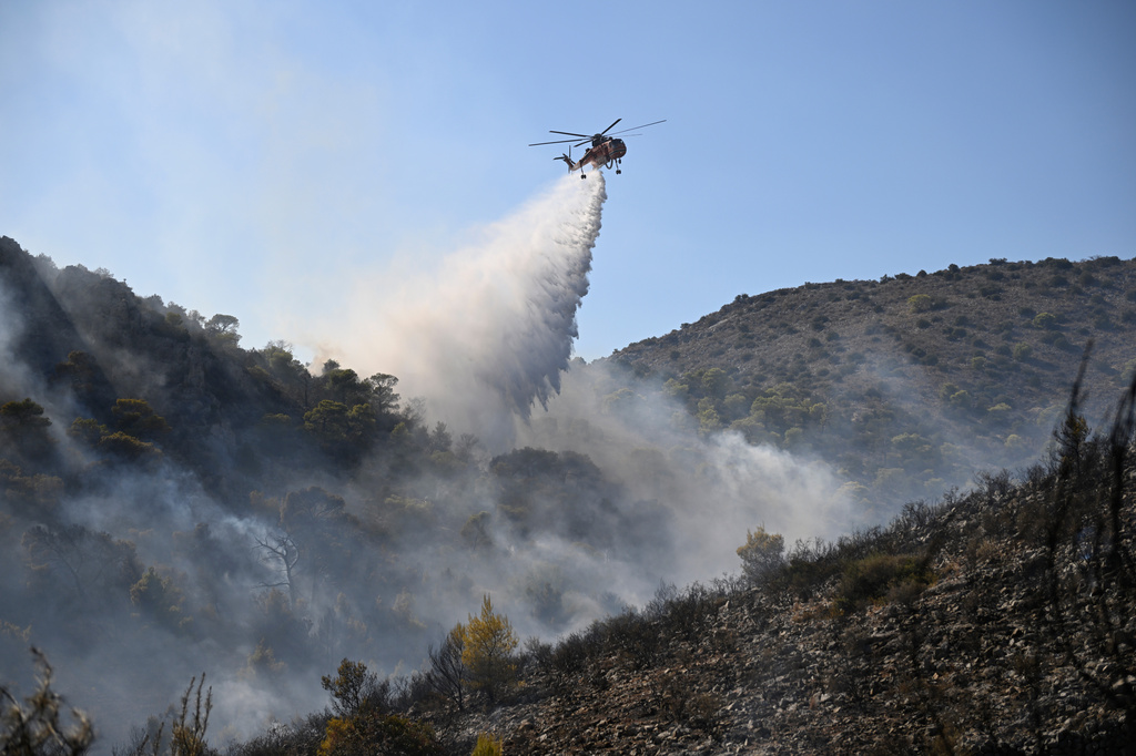 A helicopter drops water on a wildfire on the island of Salamina, west of Athens, Greece, Sunday, Aug. 16, 2026. (AP Photo/Michael Varaklas)