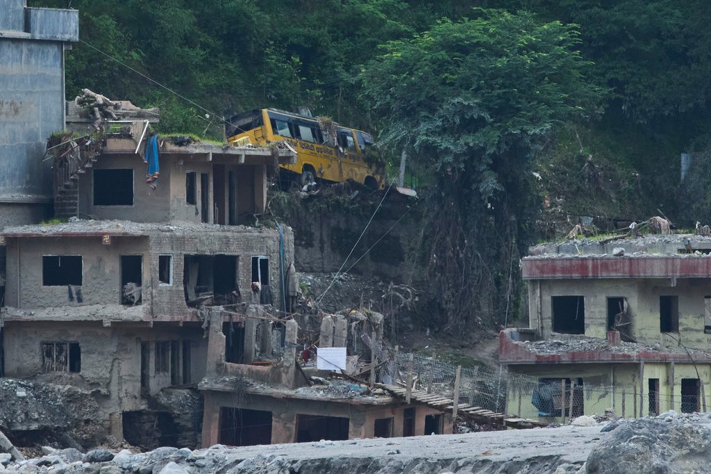A house and a school bus damaged by flash floods are seen in Betrawati, in Nepal's Nuwakot district, Wednesday, Sept. 23, 2026. (AP Photo/Niranjan Shrestha)