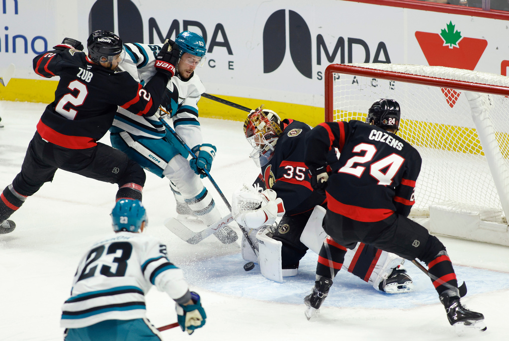 San Jose Sharks' Zack Ostapchuk (63) tries to get the puck past Ottawa Senators' goaltender Linus Ullmark (35) as Ottawa Senators' Artem Zub (2) and Ottawa Senators' Dylan Cozens (24) look on during first period NHL hockey action in Ottawa on Sunday, March 15, 2026. (Patrick Doyle/The Canadian Press via AP)