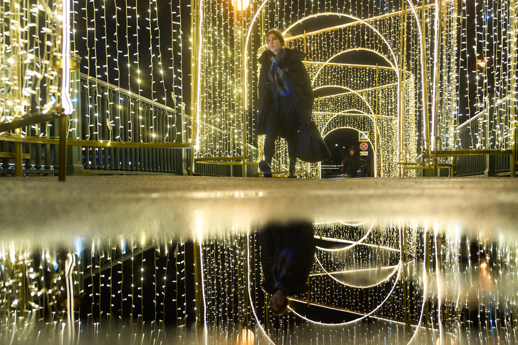 FILE - A woman walks across a bridge decorated prior to Christmas and New Year festivities in St. Petersburg, Russia, Thursday, Dec. 11, 2025. (AP Photo/Dmitri Lovetsky, File)