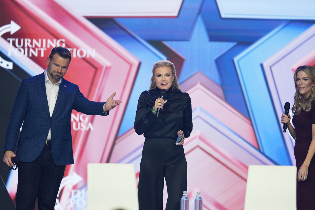 Erika Kirk, center, speaks as Jack Posobiec, left, and Megyn Kelly look on during Turning Point USA's AmericaFest 2025, Friday, Dec. 19, 2025, in Phoenix. (AP Photo/Ross D. Franklin)