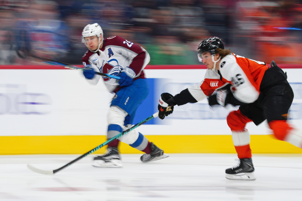 Colorado Avalanche's Nathan MacKinnon, left, takes a shot past Philadelphia Flyers' Trevor Zegras (46) during the third period of an NHL hockey game, Sunday, Dec. 7, 2025, in Philadelphia. (AP Photo/Derik Hamilton)
