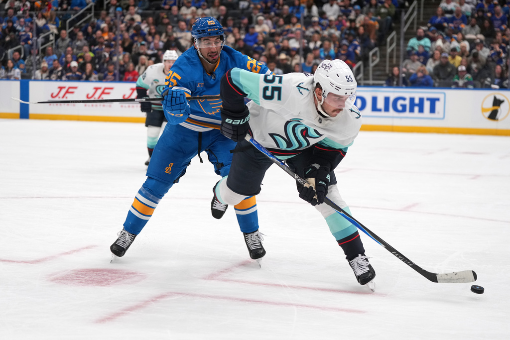 Seattle Kraken's Ryan Lindgren (55) passes as St. Louis Blues' Jordan Kyrou (25) defends during the second period of an NHL hockey game Saturday, Nov. 8, 2025, in St. Louis. (AP Photo/Jeff Roberson)