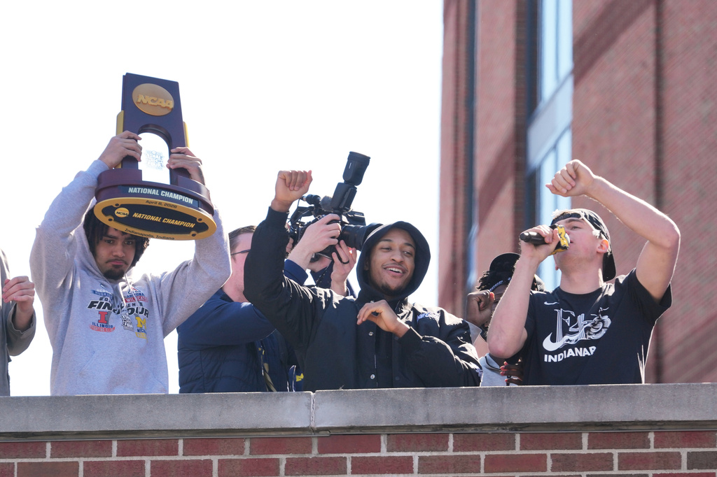 Michigan's Elliot Cadeau, left, Nimari Burnett, center, and Will Tschetter, right, celebrate as the team returns to campus Tuesday, April 7, 2026, in Ann Arbor, Mich., the day after defeating UConn at the Final Four of the NCAA college basketball tournament. (AP Photo/Paul Sancya)