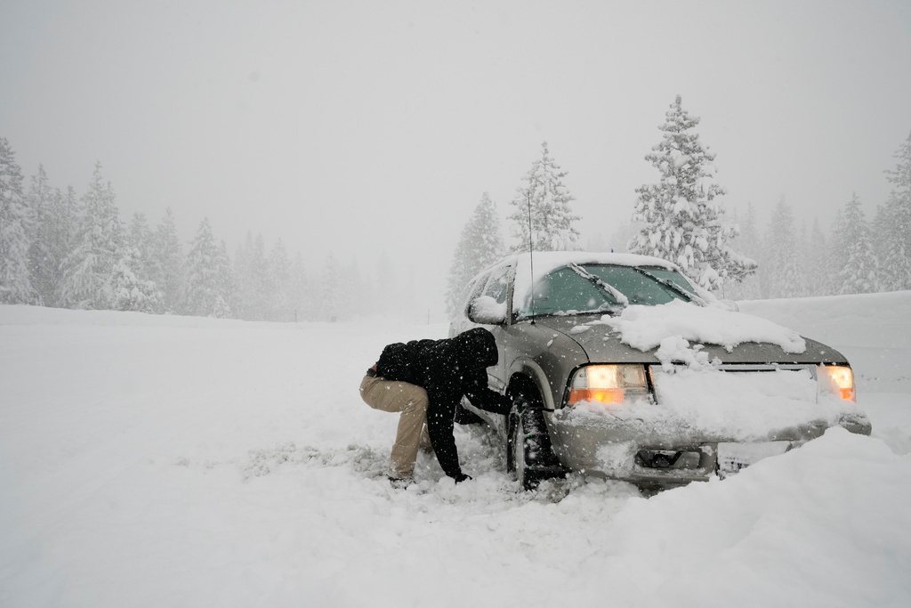 Angel Tapi tries to install chains on his tires while stuck in the snow along interstate 80 during a storm Thursday, Feb. 19, 2026, near Camp Spaulding in Placer County, Calif. (AP Photo/Godofredo A. Vásquez)