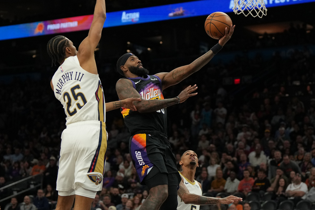 Phoenix Suns forward Royce O'Neale, center, drives past New Orleans Pelicans forward Trey Murphy III (25) during the second half of an NBA basketball game, Friday, March 6, 2026, in Phoenix. (AP Photo/Rick Scuteri)