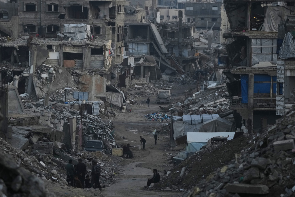 Palestinians walk amid buildings destroyed by Israeli air and ground operations in Gaza City Tuesday, Jan. 6, 2026. (AP Photo/Jehad Alshrafi)