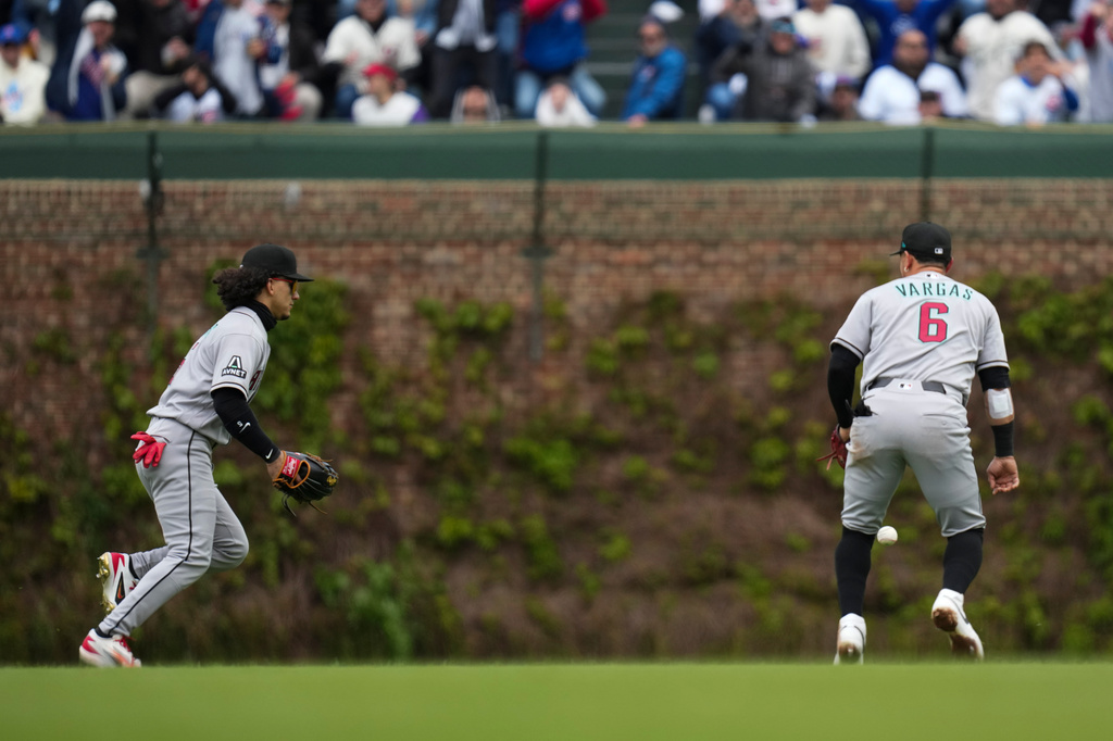 Arizona Diamondbacks center fielder Alek Thomas , left, and second baseman Ildemaro Vargas (6) chase a hit from Chicago Cubs' Carson Kelly (15) during the first inning of a baseball game Friday, May 1, 2026, in Chicago. (AP Photo/Erin Hooley)