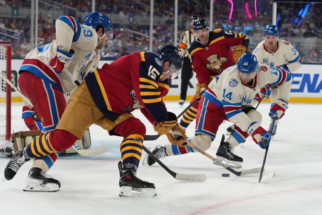 Florida Panthers center Anton Lundell (15) and New York Rangers right wing Taylor Raddysh (14) vie for the puck during the third period of the NHL Winter Classic outdoor hockey game, Friday, Jan. 2, 2026, in Miami. (AP Photo/Lynne Sladky)