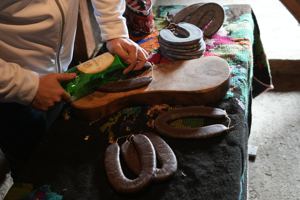 Misa Rajic irons sausage using a glass bottle in the attic of his home in Pirot, Serbia, on Feb. 13, 2026. (AP Photo/Darko Vojinovic)