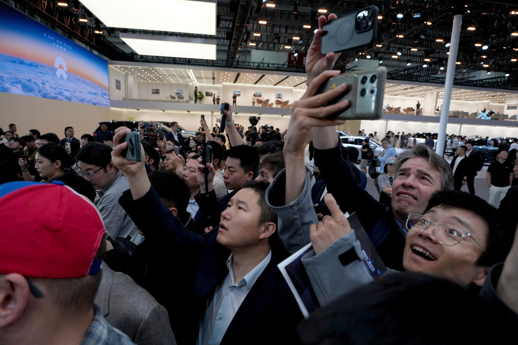 Attendees react to a flying car display at the XPENG booth during Auto China 2026 in Beijing, Friday, April 24, 2026. (AP Photo/Ng Han Guan)