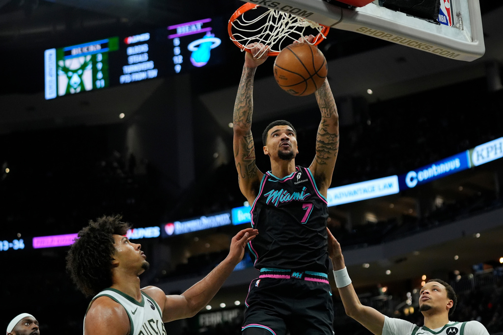 Miami Heat's Kel'el Ware (7) dunks over Milwaukee Bucks' Jericho Sims and Ryan Rollins during the second half of an NBA basketball game Tuesday, Feb. 24, 2026, in Milwaukee. (AP Photo/Aaron Gash)