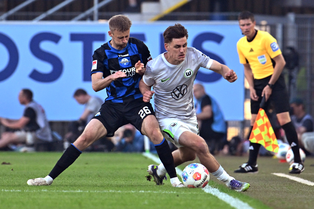 Wolfsburg's Joakim Maehle, right, and Paderborn's Sebastian Klaas, left, challenge for the ball during the soccer relegation match between German second division team SC Paderborn and German first division team VfL Wolfsburg in Paderborn, Germany, Monday, May 25, 2026. (Swen Pfoertner/dpa via AP)