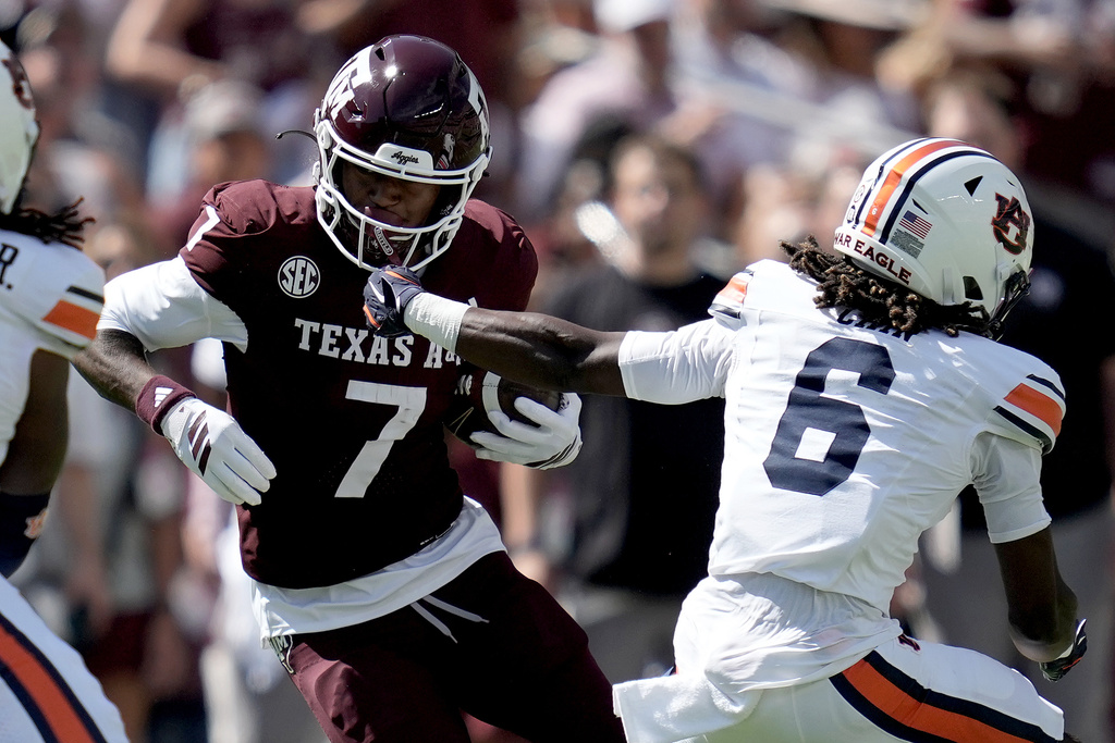 Texas A&M wide receiver KC Concepcion (7) has his face mask grabbed by Auburn linebacker Demarcus Riddick (6) after a catch and run during the first quarter of an NCAA college football game Saturday, Sept. 27, 2025, in College Station, Texas. (AP Photo/Sam Craft)
