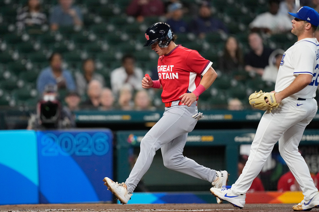 Britain's Nate Eaton, left, scores on a wild pitch by Italy pitcher Dylan DeLucia (22) during the first inning of a World Baseball Classic game, Sunday, March 8, 2026, in Houston. (AP Photo/David J. Phillip)