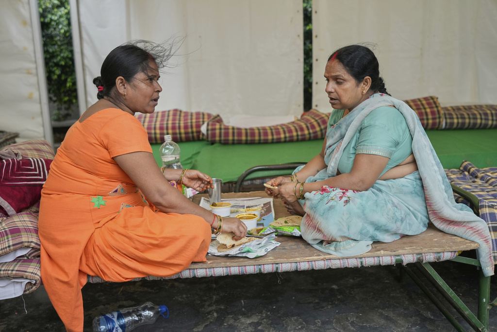 Bindu Pandey, left, eats lunch with her relative in a temporary school shelter, which houses residents displaced from the banks of the Yamuna River by incessant rain in the higher regions, in New Delhi, India, Friday, Sept. 5, 2025. (AP Photo/Manish Swarup)
