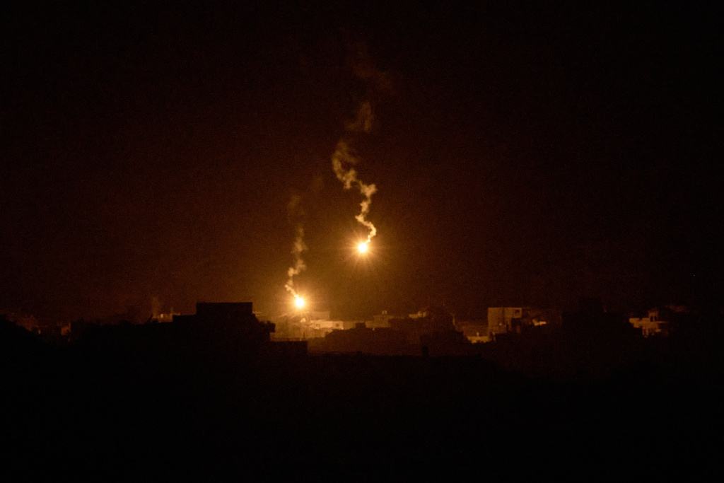 Israeli army flares drift over buildings destroyed during Israeli ground and air operations in the northern Gaza Strip, as seen from southern Israel, Wednesday, Sept. 24, 2025. (AP Photo/Leo Correa)
