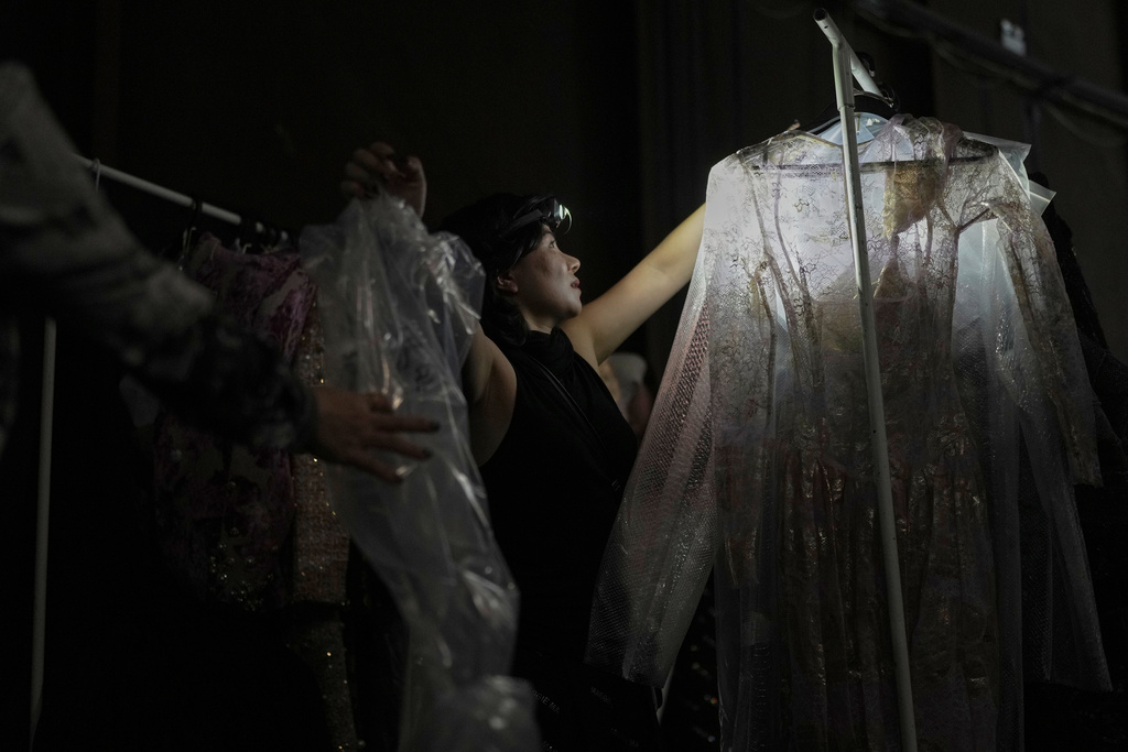 An assistant arranges designer clothing in the backstage during the SS2026 China Fashion Week in Beijing, Sunday, Sept. 7, 2025. (AP Photo/Andy Wong)