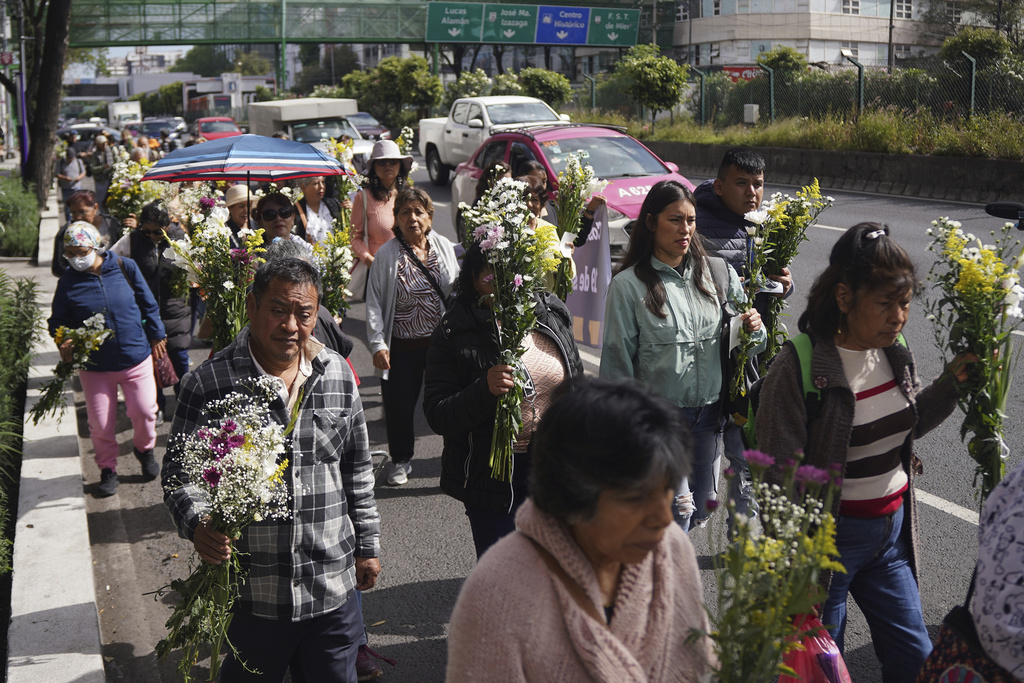 People bring flowers to site where seamstress died inside a textile plant that collapsed in the 1985 earthquake on the 40th anniversary of the quake in the Obrera neighborhood of Mexico City, Friday, Sept. 19, 2025. (AP Photo/Jon Orbach)