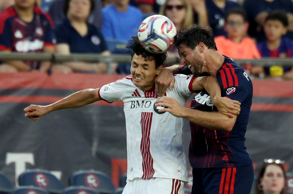Toronto FC's Dániel Sallói, left, and New England Revolution's Matt Polster, right, head the ball in the first half of an MLS soccer match, Wednesday, July 22, 2026, in Foxborough, Mass. (AP Photo/Mark Stockwell)